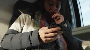 Zaman geçiren bir kadın, trenle seyahat ederken elinde telefonla internete bağlanıyor.