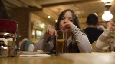 Küçük kız akşamları restoranda samanla buzlu çay içer. Lokantada çocuk içkisi