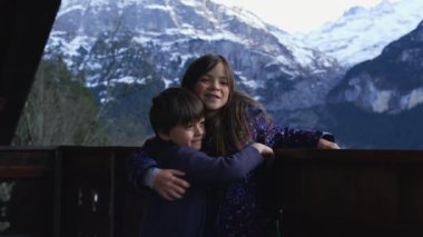 Genç Kardeşler Chalet Balkonunu kucaklıyor Alplerdeki fotoğraf için, küçük kardeşler kız kardeşe sarılıyor, aile sevgisi ve şefkat