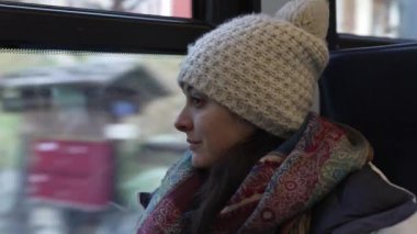 Düşünceli bir kadın, kış mevsiminde bere ve eşarp takarak tren penceresinden manzaraya bakıyor. İçe dönük yolcu