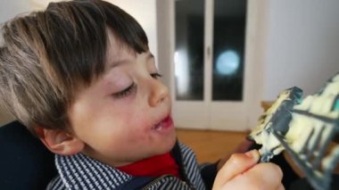 Aç Çocuk Mutfak Spatula 'sından ezilmiş patatesin tadını çıkarıyor, yemek masasında mutfak çırpıcısından püreyi yalayarak yemeği bitiriyor.