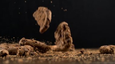 Çok sayıda çikolata parçacıkları süper yavaş çekimde masa yüzeyine düşüyor ve kırıntılar havada 1000 fp hızla uçuyor.