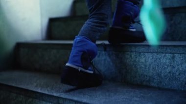 Yağmurbotlu çocuk merdivenleri tırmanıyor, yağmura hazır.