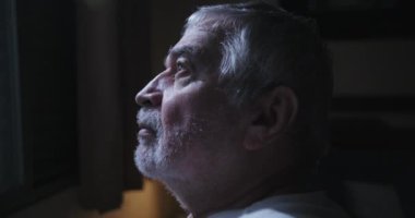 Yatakta, pencereye bakan bir adam yalnızlığı yansıtıyor. Huzurlu, sakin, düşünceli, sakin bir atmosfer.