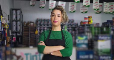 Yerel küçük işletme nalbur dükkanında silahlı kendinden emin bir kadın, organize ürün ve aletlerle çevrili, profesyonellik ve kararlılık sergiliyor.