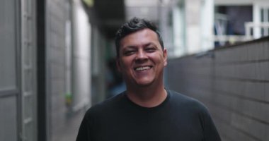 Şehir sokaklarında gülümseyen adam, neşeli yüz ifadesi, rahat açık hava atmosferi, çağdaş şehir ortamı, günlük ortamlarda dostane anlar.