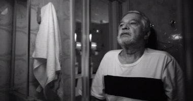 Banyodaki aynada kendi yansımasına bakan yaşlı bir adam, derin bir ızdırap ve iç çatışmada kaybolmuş, korkularla, pişmanlıklarla ve zamanın geçişiyle yüzleşiyor, siyah ve beyaz.