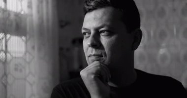 Siyah ve beyaz giyen adam, elinde dinlenen çene, çerçeveden dışarı dalgın dalgın bakıyor, yumuşak dantel perdeler ile çevrili ve fayanslı duvarları olan klasik mutfak iç mimarisi