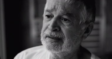 Yaşlı bir adam titreyen dudaklarıyla uzaklara bakıyor, sessizce kalp kırıklığıyla yüzleşiyor ve acı dolu bir hatıranın ağırlığıyla, siyah ve beyaz.