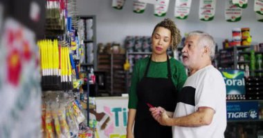 Hırdavatçıdaki raflardan araç seçmede yaşlı bir adama yardımcı olan esnaf, müşteri odaklı bir ortamda rehberlik ve desteği vurguladı