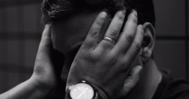 İki eliyle yüzünü örten adam, iç karışıklıktan bunalmış, umutsuzluk, umutsuzluk, duygusal mücadele, zihinsel hastalık ve izolasyonu yakın çekimde ilebiliyor.