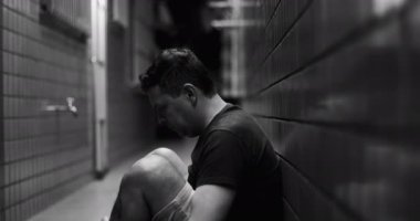 Dar bir sokakta tek başına oturan adam, derin bir yansıma, yalnızlık ve duygusal mücadele içinde, iç kargaşa, depresyon ve zihinsel sağlık sorunları ile karşı karşıya.