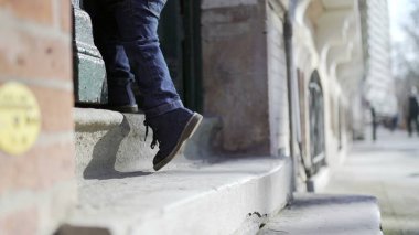 Eve adım atan bir çocuk, yeni yürümeye başlayan bir çocuk merdivenlerden eve geliyor.