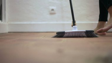 Person sweeping dirty floor with broomstick. Housework