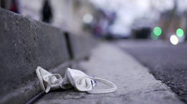 Face mask waste on ground pollution. Disposable dirty mask on sidewalk