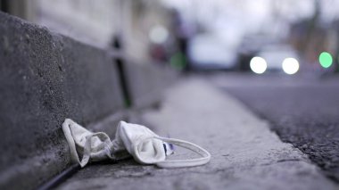 Face mask waste on ground pollution. Disposable dirty mask on sidewalk