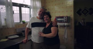 Mutfakta birlikte poz veren yaşlı bir çift, sıcak ve sevecen bir an, rahat bir ev ortamında rahat bir ev hayatı, samimi ve otantik.