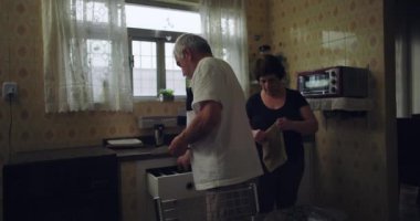 Mutfaktaki yaşlı çift günlük işleriyle meşgul, günlük ve doğal ev işleri, işbirlikçi ev hayatı, yaşlı çiftlerin günlük rutinleri, samimi ve otantik