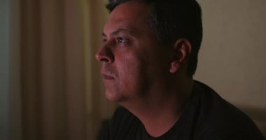 Televizyon izleyen bir adamın yan profili, odaklanmış ve meşgul, rahat ev ortamları, günlük ev eğlencesi, oturma odası anı, samimi ve doğal gözlem