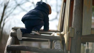 Küçük bebek, çocuk parkında tırmanmayı öğreniyor.