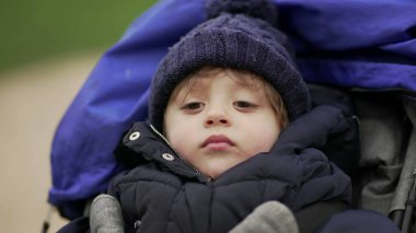 Bebek arabasındaki ciddi bebek, kışlık giysiler giyiyor.