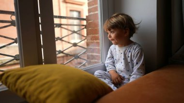 Bebek bebek pencerenin kenarından dışarıya bakıyor.