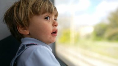 Trenle seyahat eden çocuk, pencereden dışarı bakan küçük çocuk geçen manzaraya bakıyor.