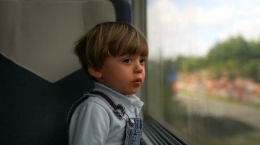 Trenle seyahat eden çocuk pencereye yaslanmış hayal kuruyor ve manzaranın geçtiğini görüyor.