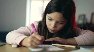 8 yaşındaki bir kız çocuğu kalemle çizim yapmaya çok odaklanır. Yüzündeki ifade yoğun ve odaklıdır. Bu an, çocuğun sanatsal meşgalesindeki nişanını yakalar.