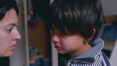 Anne ve çocuk duygusal bir anda evde, çocuk üzgün bir ifade sergilerken anne izliyor. ebeveyn ve çocuk arasındaki hassas ve destekleyici etkileşim