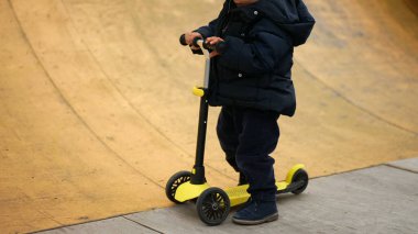 Üç tekerlekli scooter kullanan küçük bir çocuk. Bebek oyuncağa biner