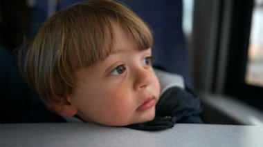 Düşünceli çocuk vagon penceresinden dışarı bakarak trende hayal kuruyor.