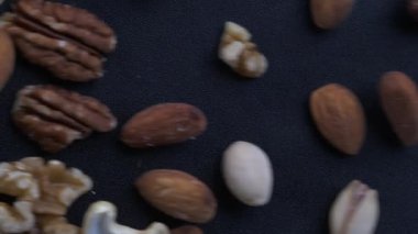 Nut Variety in Motion - Macro Close-Up of Bamonds, Walnuts, Pecans, Cashews, Fındık ve Pistachios, Masa Arasından Kayarken Tepeden Bakış