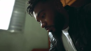 Genç bir siyah Latin adam yatak odasındaki cep telefonu ekranına bakıyor. Afrika kökenli 20 'li yaşlarda modern teknoloji ile uğraşan, yakından profil yüzü olan biri.