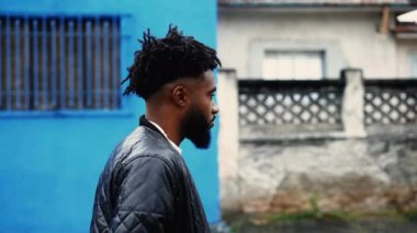 Genç siyahi bir adam şehirde yürüyor, 20 'li yaşlardaki Afro-Amerikan' ın derin derin bakışlı görüntülerini yakından çekiyor.