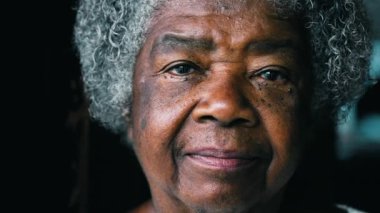 Ciddi bir siyahi yaşlı kadın kamera karşısında deneyimli ve bilge görünüyor. Kırışıklıkları ve gri saç portresi olan 80 'li yaşlarda Afro-Amerikalı bir kadın.