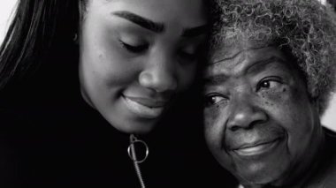 Nesiller arası bağ - Afrikalı Amerikalı torun ve kıdemli büyükanne sevecen bir anda, genç kız yaşlı büyükannesine bakıyor, siyah ve beyaz