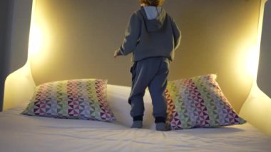 Otel Yatağında Neşeli Çocuk Atlama - Tatil Eğlencesi. Küçük çocuk hoplayıp zıplıyor