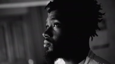 20 'li yaşlardaki düşünceli Afro-Amerikan Adam, Pencerenin Siyah-Beyaz Yansıması. Zihninde derin bir yansıması olan genç siyahi bir adamın yakın plan yüzü. Düşünceli ifade