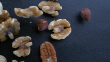 Masada yavaş çekimde kayan fındık çeşitleri badem, ceviz, ceviz, fındık, fındık ve fıstık karışımı yakın çekim görüntüsü.