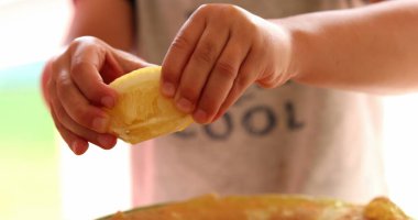 Child hands squeezing lemon into food plate