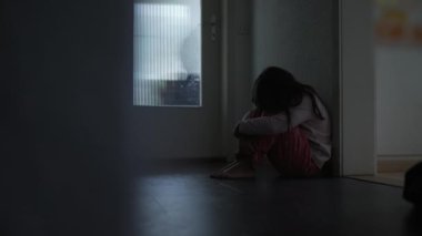 Hüzünlü, yalnız çocuk iç karartıcı, kasvetli, kasvetli bir şekilde evinin koridorunda oturmuş kaygı ve depresyonla yüzünü örtüyor. Çocukluğunda akıl hastalığıyla mücadele eden çocuk