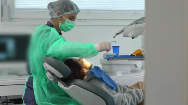 Klinikte çocuk dişlerini tedavi eden konsantre kadın diş hekimi. Profesyonel işgücü