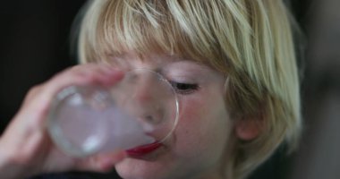 Sarışın çocuk bir bardak su içiyor.