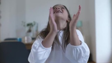 Enerjik mutlu çocuk gülümseyen kameraya doğru el çırpıyor. Küçük bir kız başarıyı ve iyi haberi kutluyor.