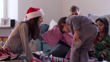 Pijamalı samimi aile Noel 'i. Oturma odasında hediyeler açılıyor. Annem SKI pantolonlarını hediye olarak gösteriyor.