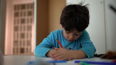 Yatmadan önce evde resim çizen konsantre küçük çocuk. Yatak odasındaki masada çocuk boyası. Çocukluk sanatı boş zaman aktivitesi