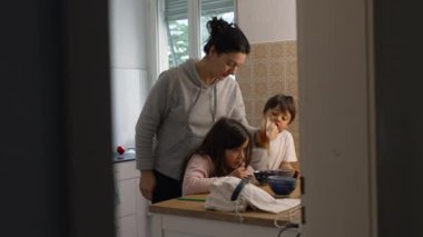 Bir annenin iki çocuğuyla mutfakta yemek hazırlarken çekilmiş gizli bir ev hayatı sahnesi. Küçük erkek ve kız kardeş, anne babasıyla konuşurken, o da kaseye bal döker.