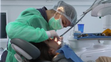 Dişçi kliniğinde çalışan kadın diş hekimi. Çocuğun ağız sağlığıyla ilgilenen konsantre profesyonel bir işçi.