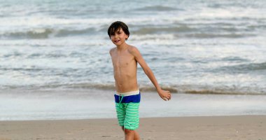 Young boy walking towards camera at the beach